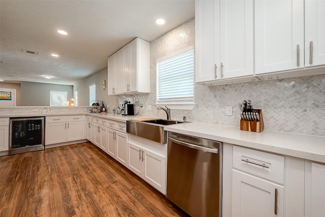 kitchen with light countertops, stainless steel dishwasher, white cabinetry, a sink, and beverage cooler