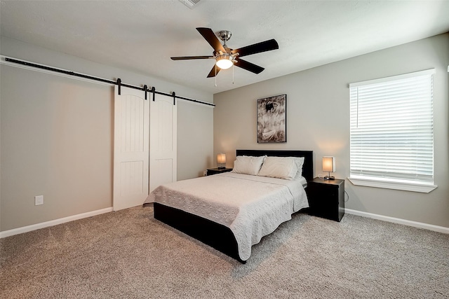 bedroom featuring light carpet, a barn door, and baseboards