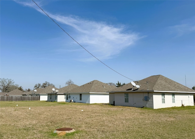 rear view of property featuring fence and a lawn