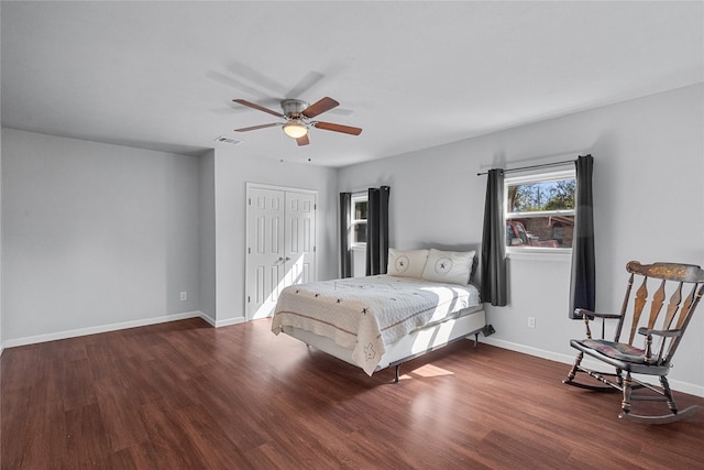 bedroom featuring dark wood-style flooring, a closet, visible vents, a ceiling fan, and baseboards