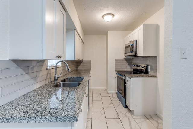 kitchen with marble finish floor, stainless steel appliances, a sink, and white cabinetry