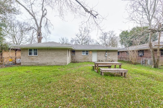 rear view of house with brick siding, a lawn, and fence