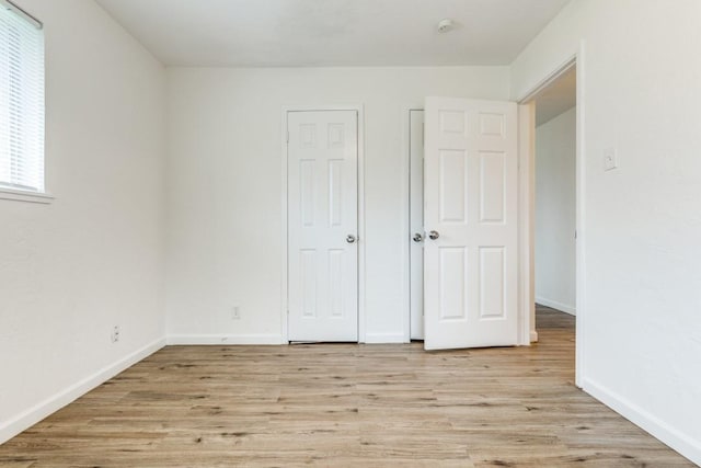 unfurnished bedroom featuring light wood finished floors and baseboards