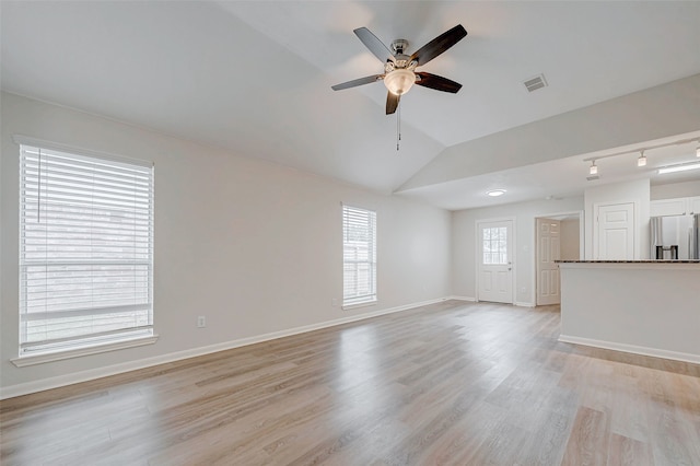 unfurnished living room featuring visible vents, light wood-style floors, a ceiling fan, vaulted ceiling, and baseboards