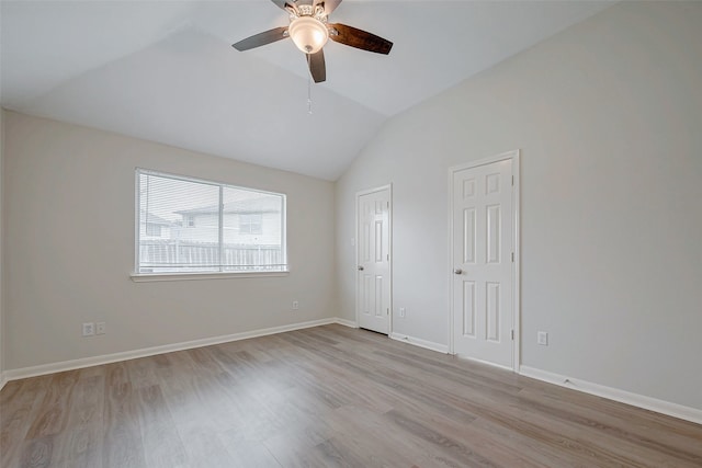 unfurnished room featuring lofted ceiling, light wood-style flooring, baseboards, and a ceiling fan