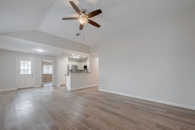 unfurnished living room with lofted ceiling, visible vents, light wood-style flooring, ceiling fan, and baseboards