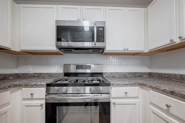 kitchen featuring white cabinets, tasteful backsplash, dark stone counters, and stainless steel appliances