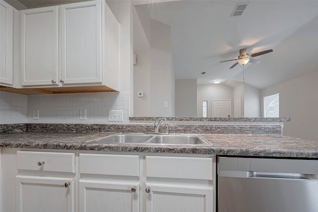 kitchen with dark countertops, white cabinets, a sink, and visible vents