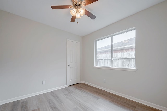 empty room with light wood-type flooring, a ceiling fan, and baseboards