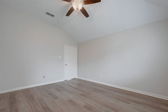 spare room featuring ceiling fan, visible vents, baseboards, vaulted ceiling, and light wood finished floors