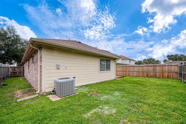 rear view of property with brick siding, a lawn, cooling unit, and a fenced backyard