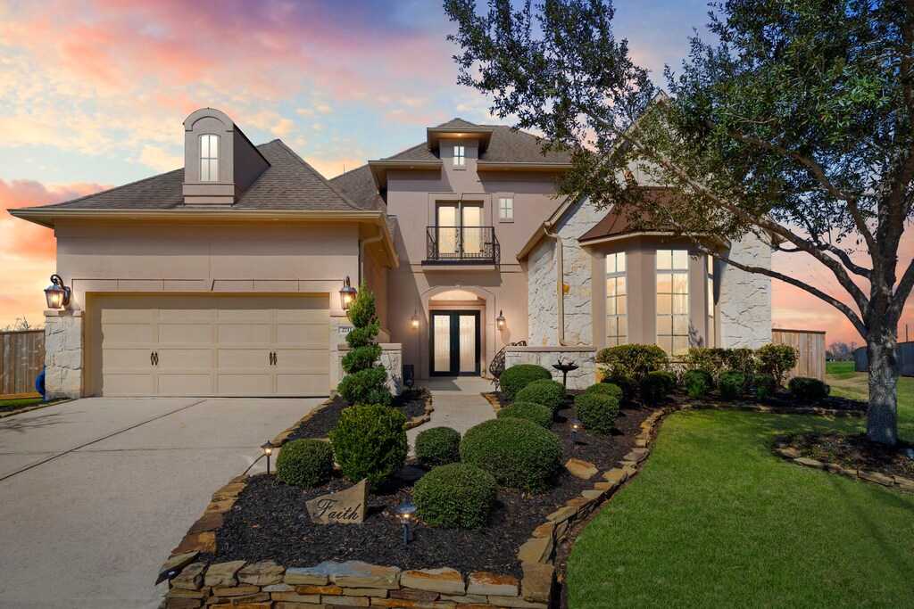 2711 Big Vine Ct, Missouri City, TX 77459 - french country style house featuring driveway, an attached garage, a balcony, and stucco siding