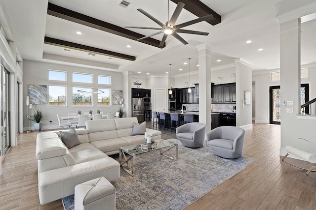 living room with light wood finished floors, beam ceiling, decorative columns, and baseboards