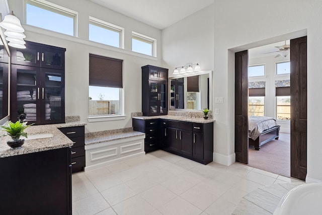 ensuite bathroom featuring connected bathroom, a towering ceiling, ceiling fan, tile patterned flooring, and vanity