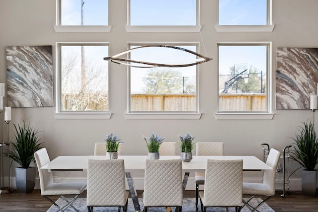 dining area with a wealth of natural light, a towering ceiling, and wood finished floors