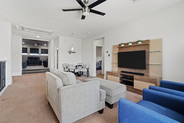 carpeted living room with attic access, baseboards, and a ceiling fan