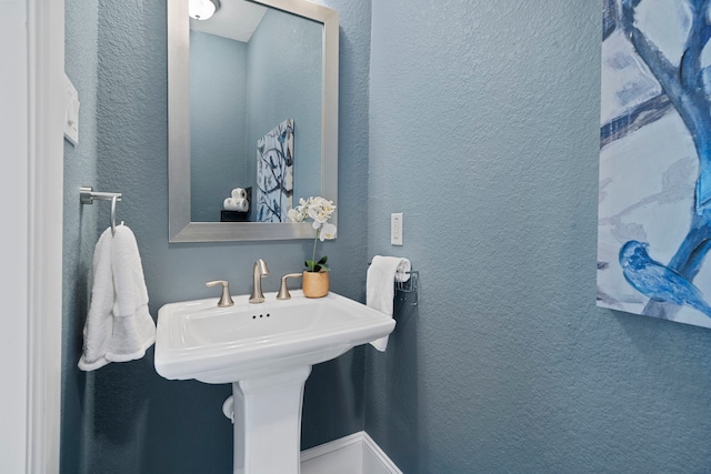 bathroom featuring a textured wall and a sink