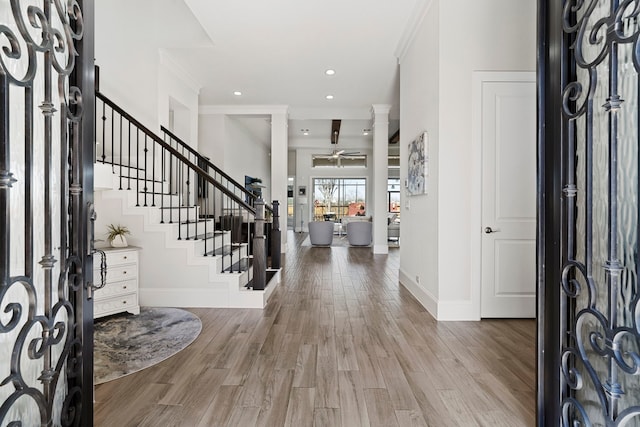 foyer entrance with baseboards, crown molding, stairway, and wood finished floors