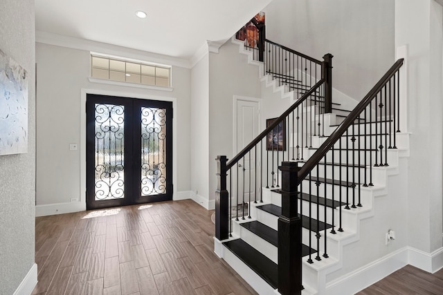 entryway featuring a towering ceiling, baseboards, wood finished floors, and french doors