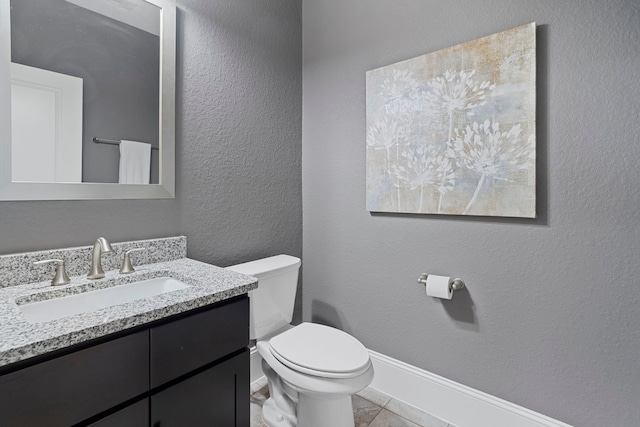 half bathroom with a textured wall, vanity, and toilet