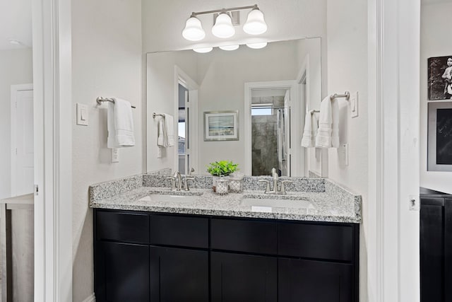 full bathroom with double vanity, a shower stall, and a sink