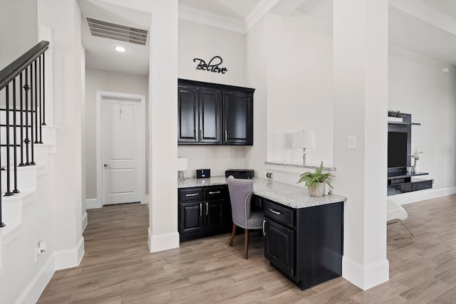 bar featuring visible vents, baseboards, built in study area, light wood-style flooring, and ornamental molding