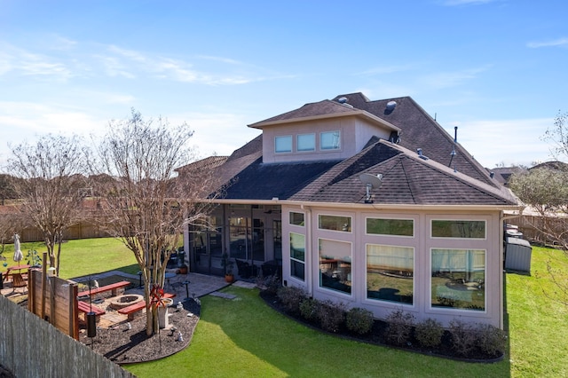 rear view of property with a patio, a shingled roof, a lawn, a sunroom, and fence