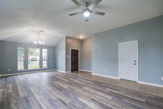 unfurnished living room with light wood-type flooring, ceiling fan with notable chandelier, baseboards, and lofted ceiling