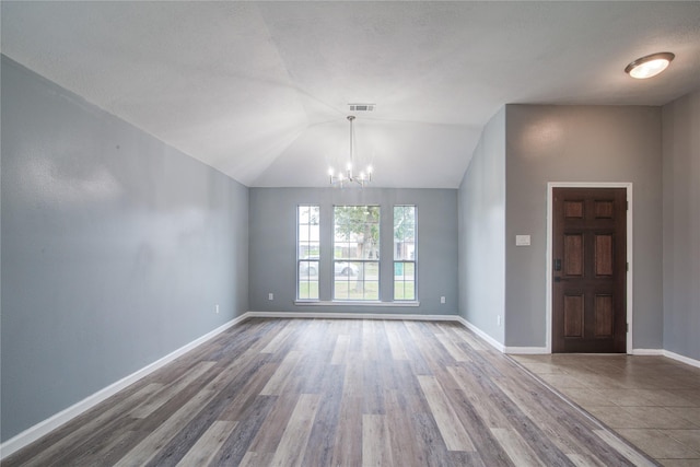 interior space featuring lofted ceiling, a chandelier, wood finished floors, visible vents, and baseboards