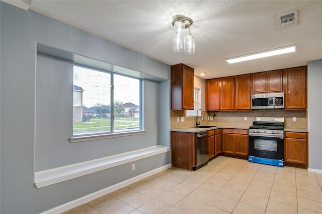 kitchen featuring pendant lighting, visible vents, light countertops, backsplash, and appliances with stainless steel finishes