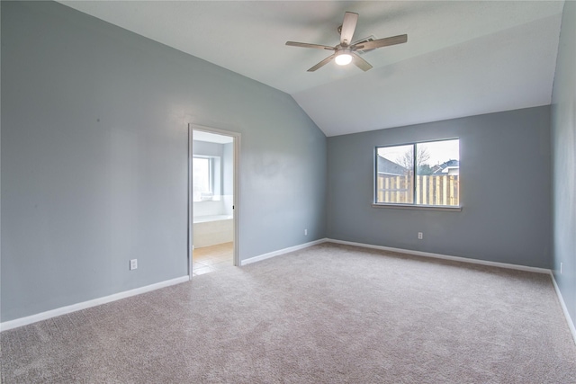 spare room featuring baseboards, vaulted ceiling, a ceiling fan, and light colored carpet