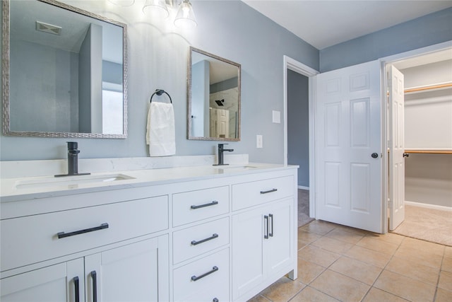 bathroom with visible vents, double vanity, a sink, and a walk in closet