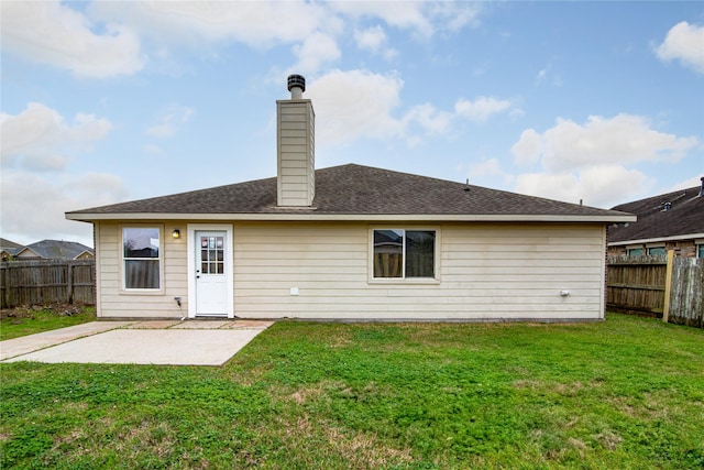 back of property featuring a chimney, a shingled roof, a lawn, a patio area, and a fenced backyard