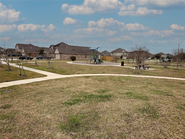 view of community featuring playground community, a lawn, and a residential view