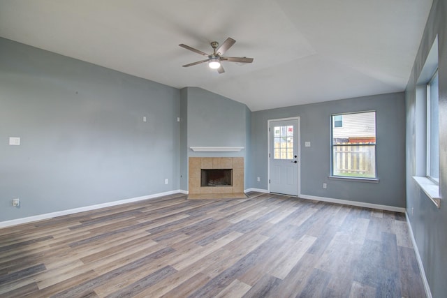 unfurnished living room with ceiling fan, a fireplace, baseboards, and wood finished floors