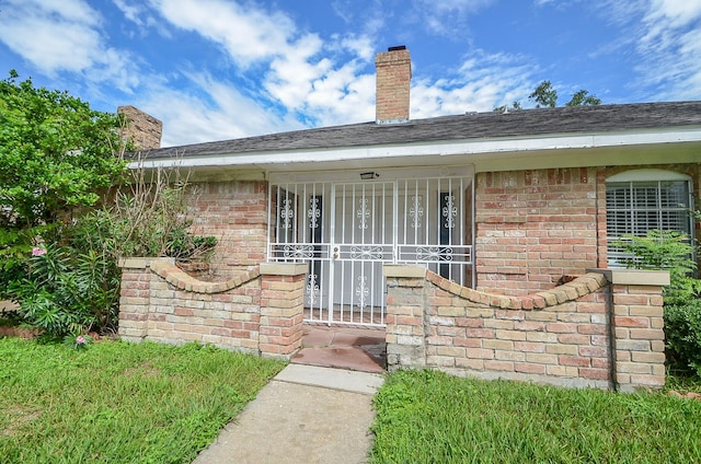 property entrance featuring a chimney and brick siding