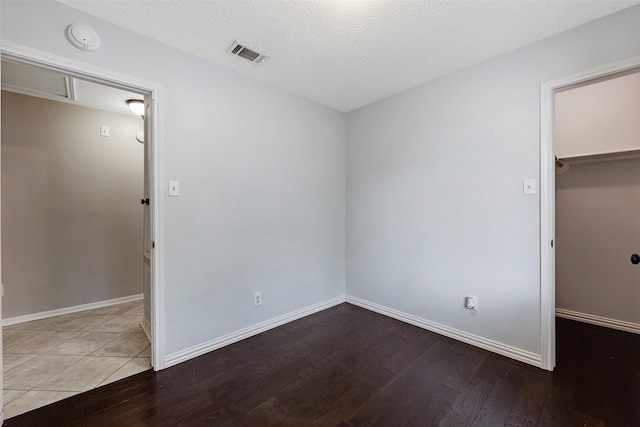 28907 Sedgefield St, Spring, TX 77386 - unfurnished bedroom with a walk in closet, wood finished floors, baseboards, a closet, and a textured ceiling