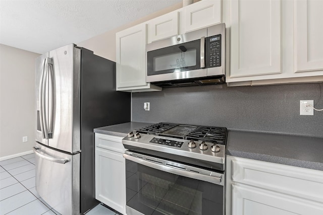 28907 Sedgefield St, Spring, TX 77386 - kitchen with appliances with stainless steel finishes, dark countertops, white cabinetry, and tile patterned flooring