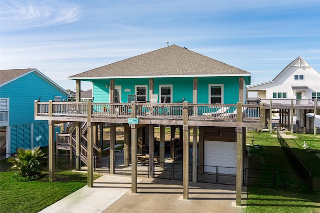 rear view of property with driveway, a shingled roof, a yard, a porch, and a carport