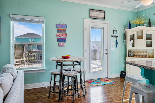 dining area with ornamental molding, dark wood finished floors, baseboards, and a ceiling fan