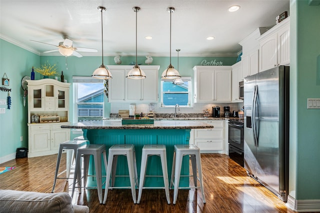 kitchen with a center island, stainless steel appliances, white cabinetry, dark stone counters, and a kitchen breakfast bar