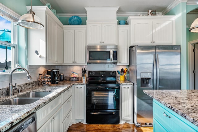 kitchen with appliances with stainless steel finishes, a sink, decorative light fixtures, and white cabinets