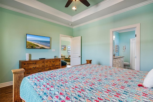 bedroom with dark wood finished floors, a raised ceiling, ceiling fan, ornamental molding, and ensuite bathroom