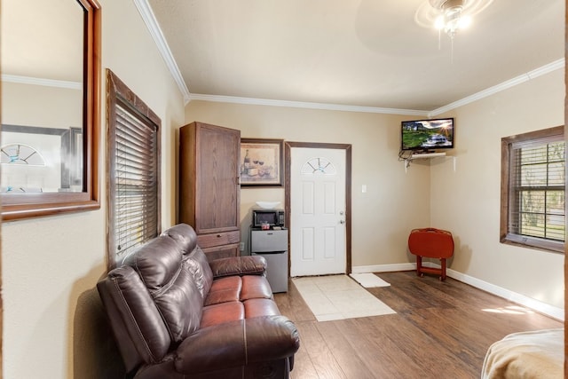 living area with ceiling fan, crown molding, baseboards, and wood finished floors