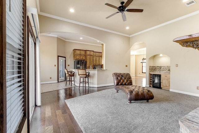 living area with dark wood-style floors, a glass covered fireplace, visible vents, and baseboards