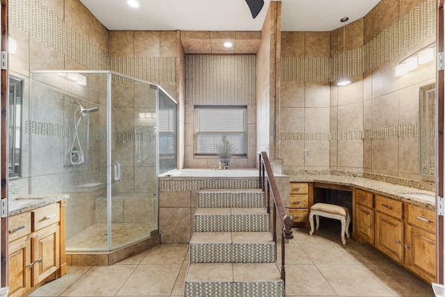 bathroom with tile walls, a shower stall, vanity, and tile patterned floors