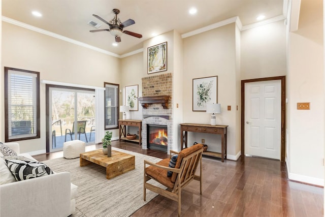 living area with baseboards, ornamental molding, wood finished floors, and a glass covered fireplace