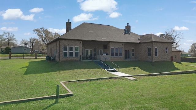 back of property featuring a yard, brick siding, a chimney, and cooling unit