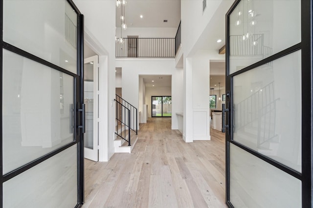 foyer entrance featuring visible vents, a high ceiling, stairway, and wood finished floors