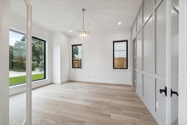 empty room featuring baseboards, an inviting chandelier, light wood-style flooring, and recessed lighting